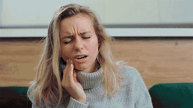 Woman holding her cheek in discomfort from dental pain
